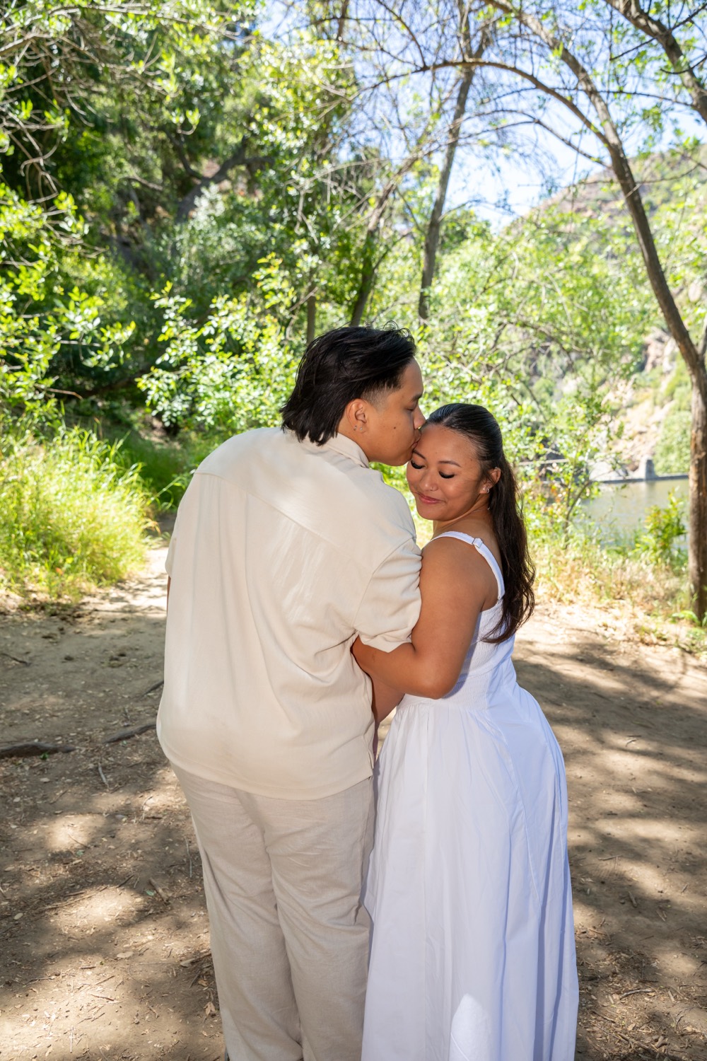 Neal kissing Monique on the forehead by the river